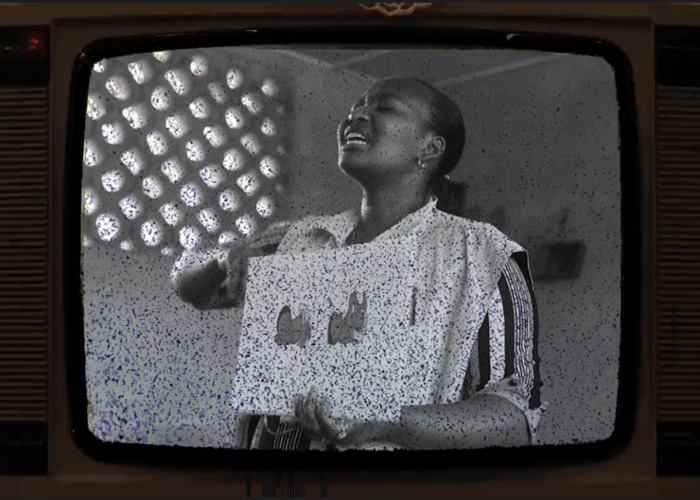 An Action Against Hunger staff member holds up a sign in a stylised old television.