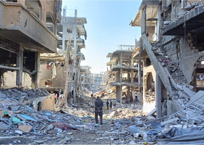 People standing in rubble in Gaza City.