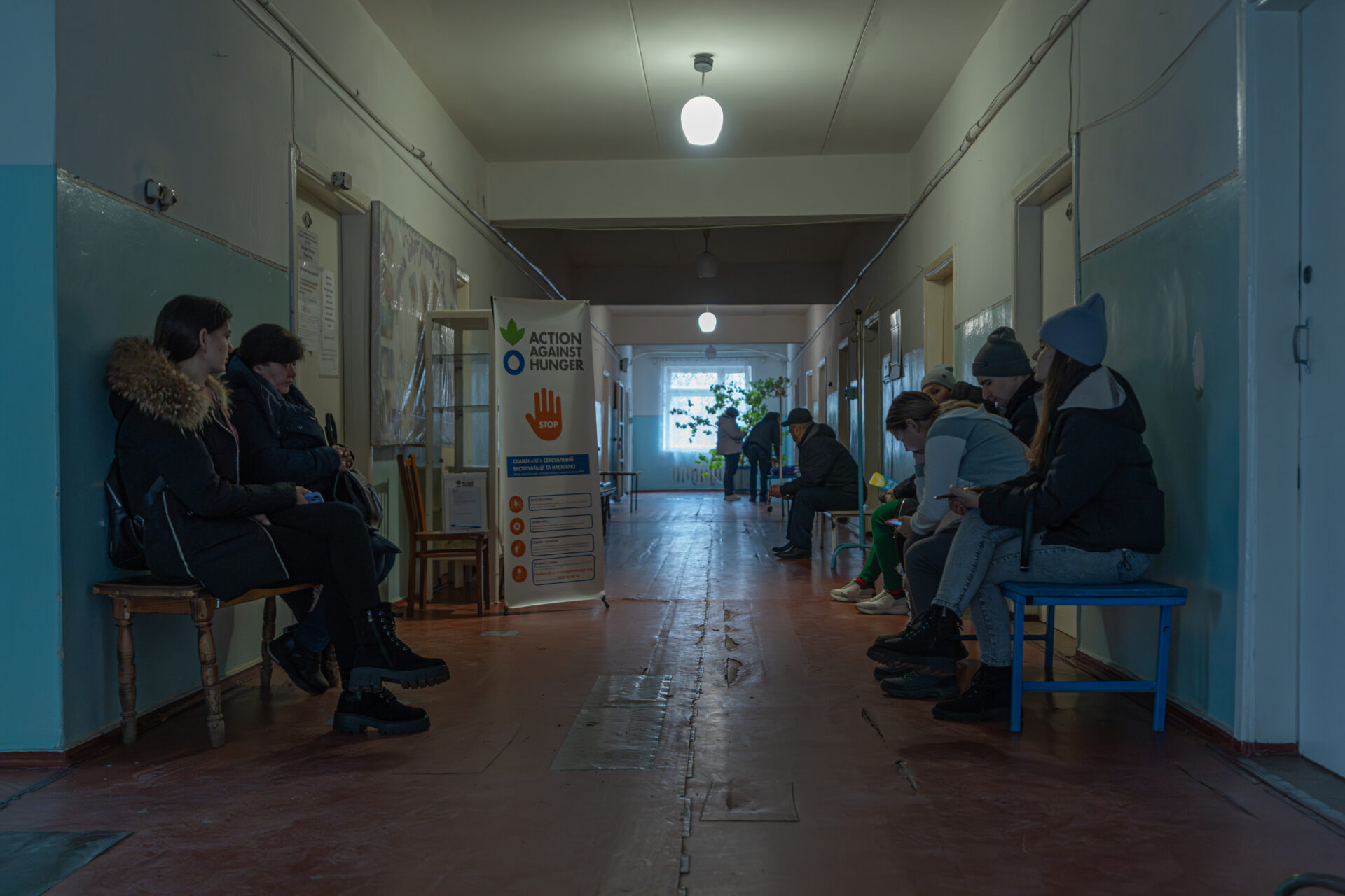 People in Ukraine waiting for aid in hospital corridor.