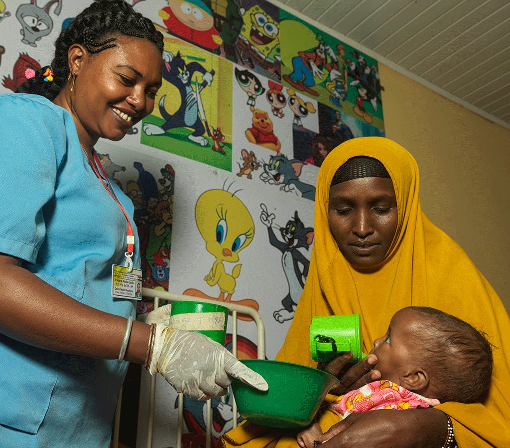 Fardosa receives therapeutic milk in a large cup specifically for severely malnourished cases from Action Against Hunger trained nurse Ware Arbale at Yabelo General Hsopital.
