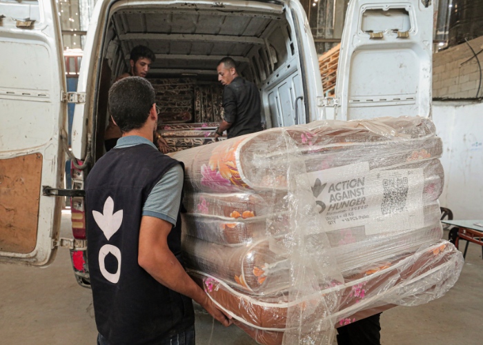 Aid workers loading mattresses into an aid van in Gaza.