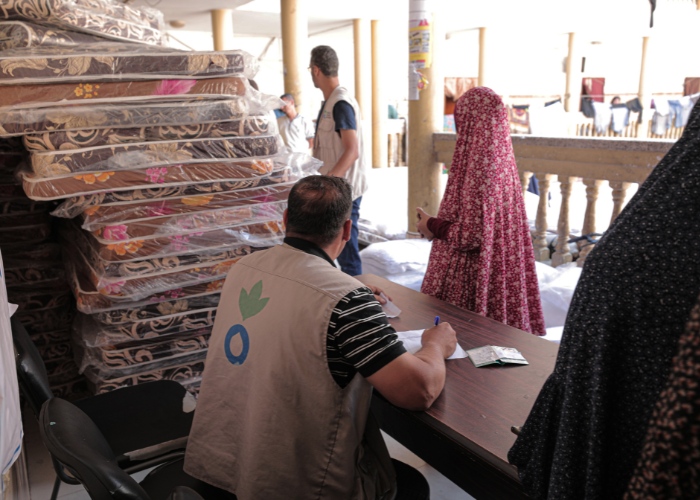 Woman in Gaza receiving mattress from aid worker.
