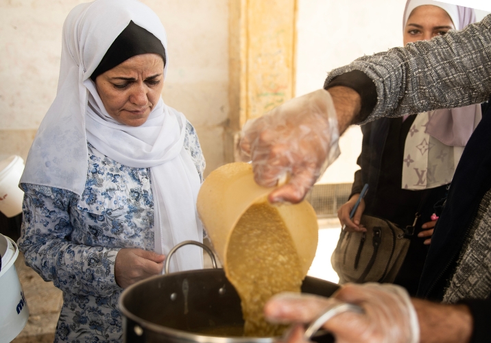 Woman in headscarf getting food aid meal from Action Against Hunger.
