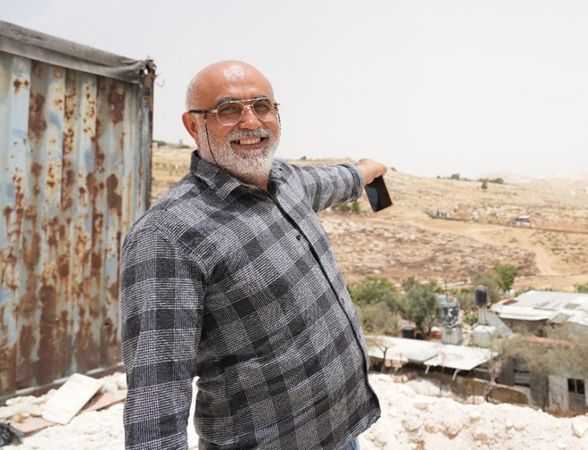 Mamoun looks at the camera and points towards his farmland in the West Bank.
