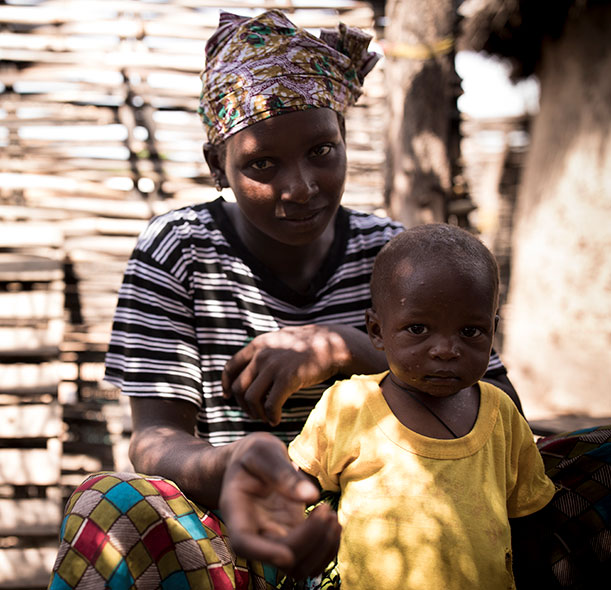 Simbo, a boy who recovered from malnutrition thanks to support from Action Against Hunger, with his mum in a village in Mali.
