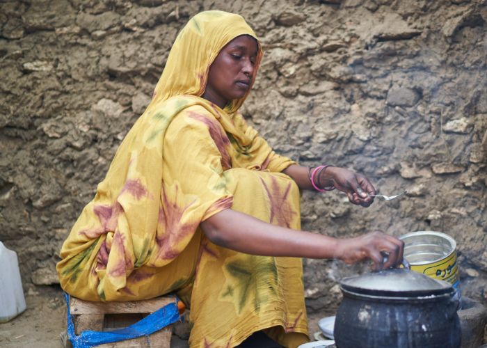 Sudanese refugee cooking food on stove supported by Action Against Hunger.