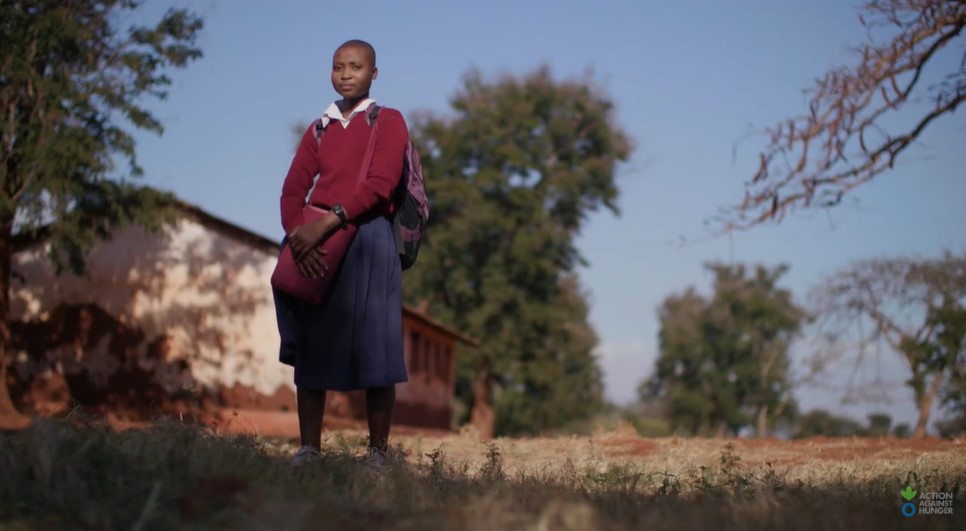 Lulu, a girl from Tanzania, wearing school uniform in rural surrounding.