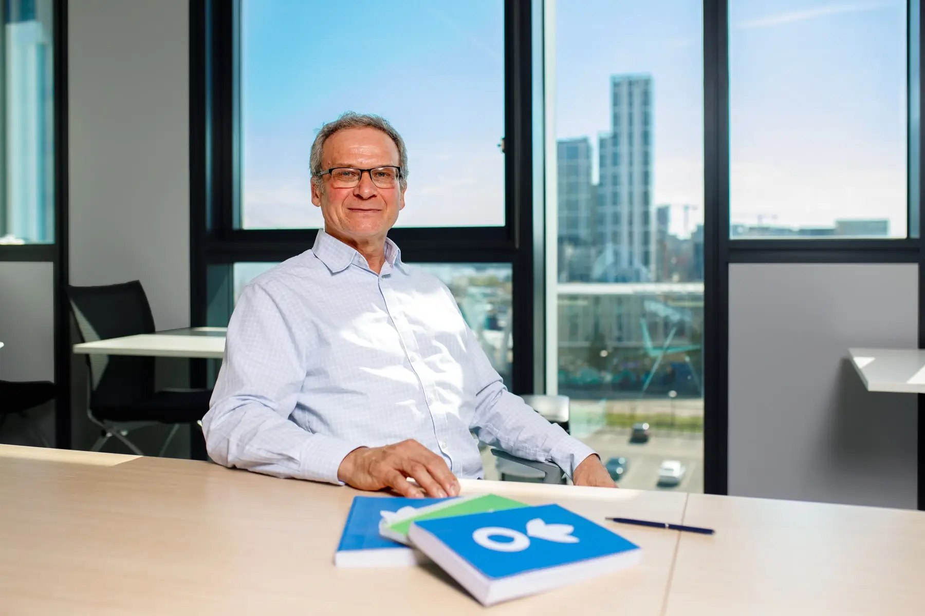 Jean-Michel sat in office in front of London skyline with Action Against Hunger notebooks. 